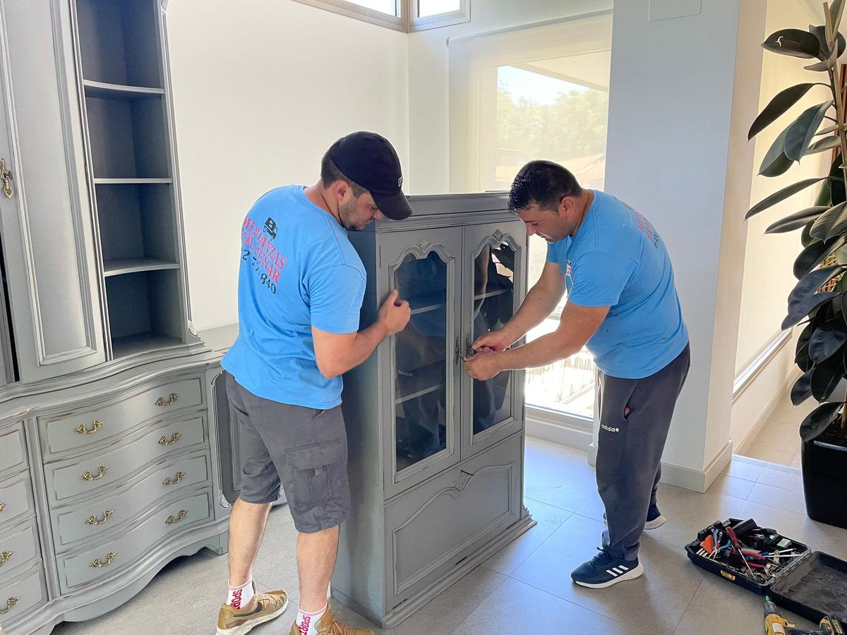 Dos operarios de Mudanzas Colmenar montando una vitrina
